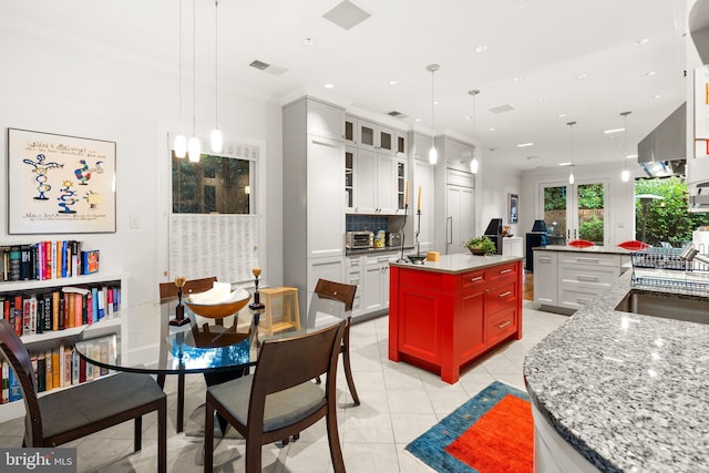 kitchen with white cabinetry, a kitchen island, backsplash, and decorative light fixtures