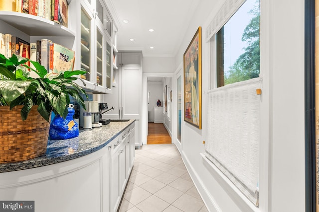 hallway featuring light tile patterned flooring, crown molding, and sink