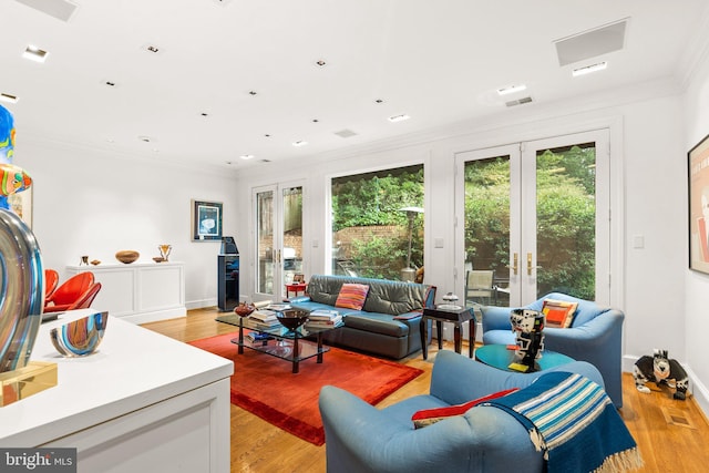 living room featuring crown molding, light hardwood / wood-style flooring, and french doors