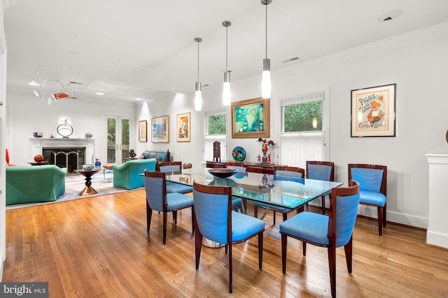 dining area featuring ornamental molding, a fireplace, and light hardwood / wood-style flooring