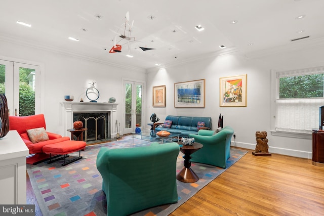 living room with french doors, ornamental molding, light hardwood / wood-style floors, and plenty of natural light