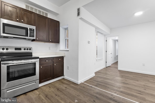 kitchen featuring dark brown cabinetry, appliances with stainless steel finishes, and dark hardwood / wood-style floors