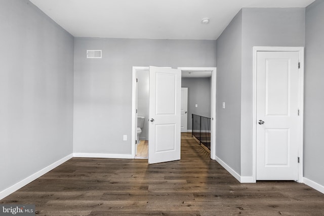 unfurnished bedroom with dark wood-type flooring and ensuite bath