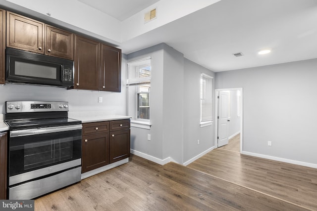 kitchen with dark brown cabinets, light hardwood / wood-style flooring, and electric stove