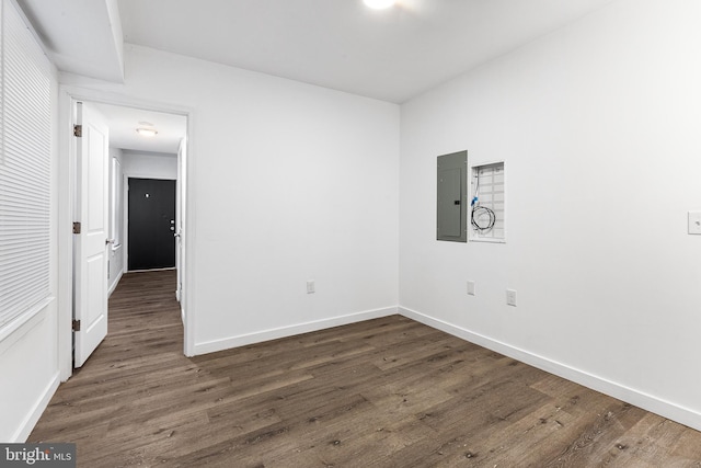 empty room with dark hardwood / wood-style flooring and electric panel