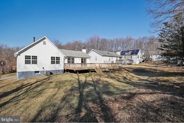 rear view of property featuring a wooden deck and a lawn