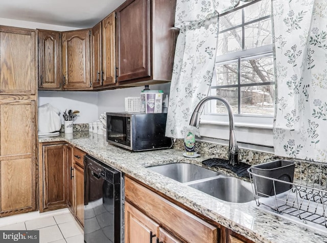 kitchen with light stone countertops, light tile patterned floors, black dishwasher, and sink