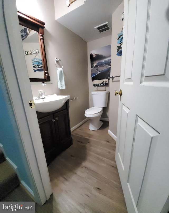 bathroom featuring toilet, wood-type flooring, and vanity