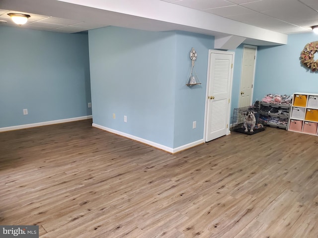 basement featuring wood-type flooring and a paneled ceiling