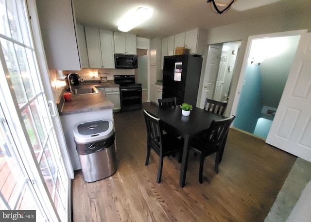 kitchen with white cabinetry, plenty of natural light, light wood-type flooring, black appliances, and sink