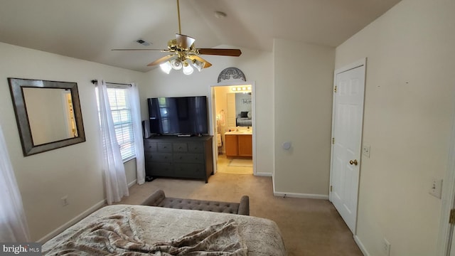 carpeted bedroom with vaulted ceiling, ceiling fan, and ensuite bath