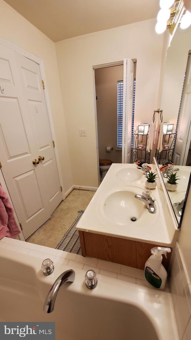 bathroom with toilet, vanity, and tile patterned floors