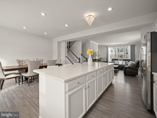 kitchen with hardwood / wood-style flooring, white cabinets, a center island, and stainless steel refrigerator