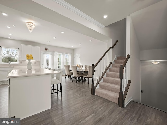 kitchen with a center island, crown molding, a kitchen breakfast bar, white cabinets, and dark hardwood / wood-style flooring