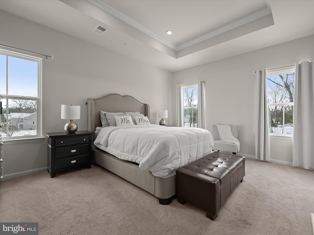 bedroom with crown molding, light colored carpet, and a tray ceiling