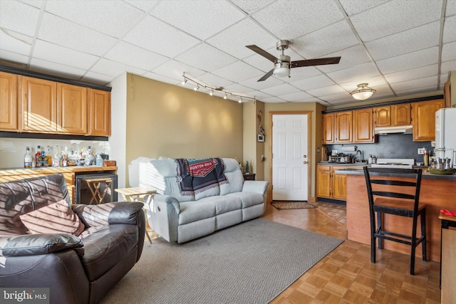 living room with ceiling fan, wine cooler, a paneled ceiling, bar area, and parquet floors