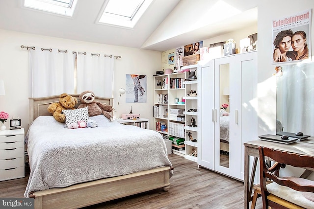 bedroom with hardwood / wood-style flooring and vaulted ceiling with skylight