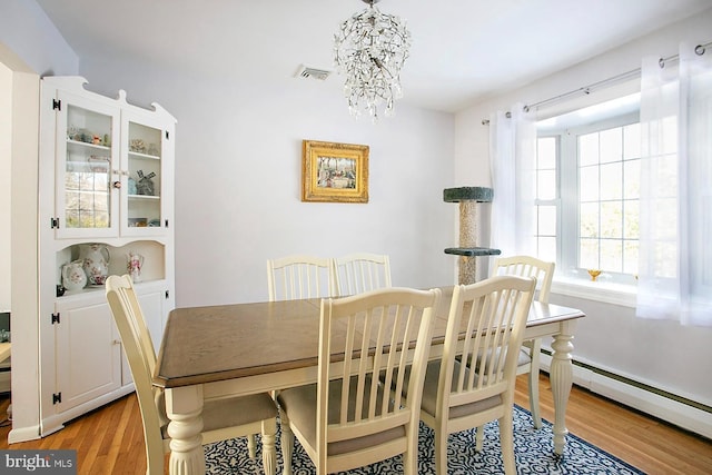 dining room featuring a baseboard radiator, an inviting chandelier, and light hardwood / wood-style flooring