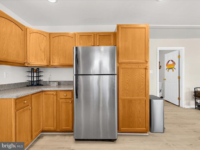 kitchen with light hardwood / wood-style flooring and stainless steel refrigerator