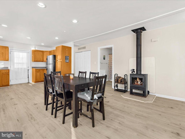 dining room with light wood-type flooring and a wood stove