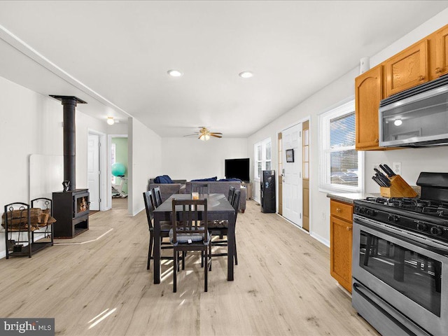 dining space featuring ceiling fan, a wood stove, and light hardwood / wood-style flooring