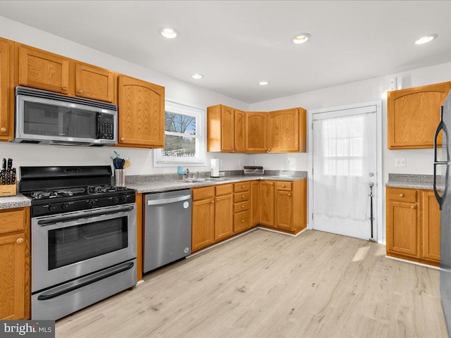 kitchen with sink, stainless steel appliances, and light wood-type flooring