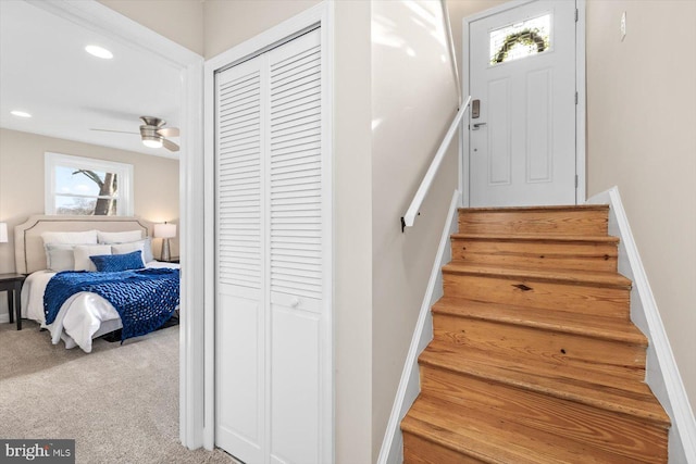 stairway with carpet floors and ceiling fan