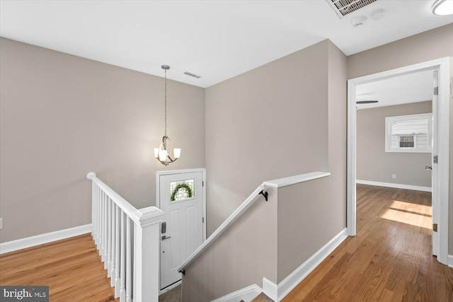 stairs with wood-type flooring and a chandelier