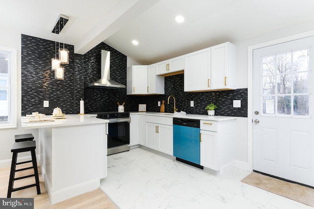 kitchen featuring stainless steel appliances, white cabinetry, hanging light fixtures, and wall chimney exhaust hood