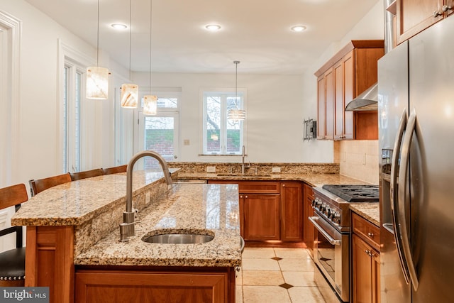 kitchen with stainless steel appliances, a breakfast bar, sink, and decorative light fixtures