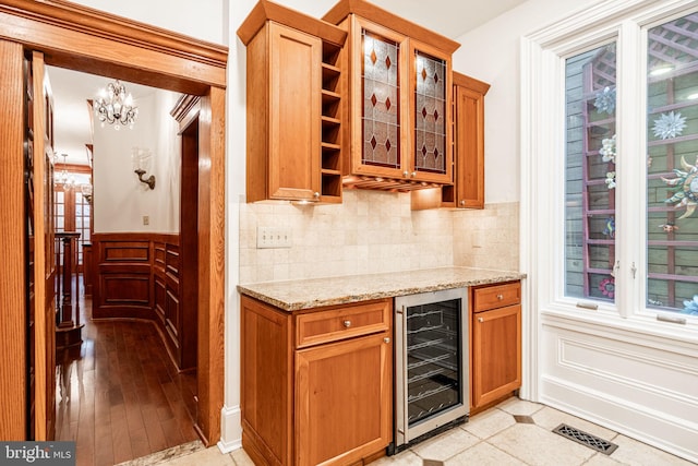 kitchen with light stone counters, beverage cooler, an inviting chandelier, and light tile patterned floors