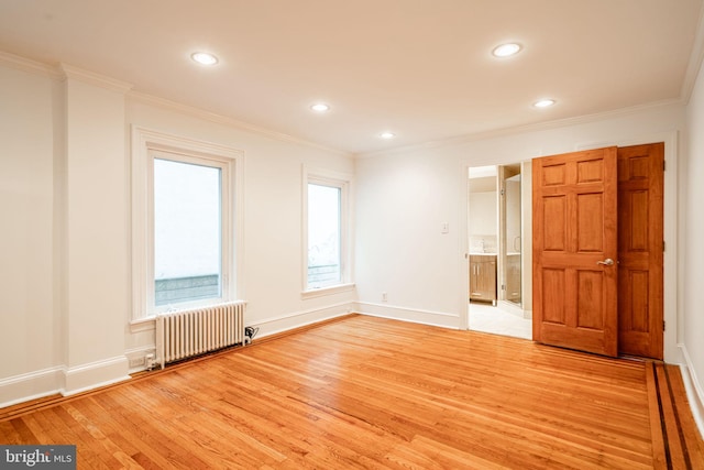 unfurnished room with radiator, ornamental molding, and light wood-type flooring