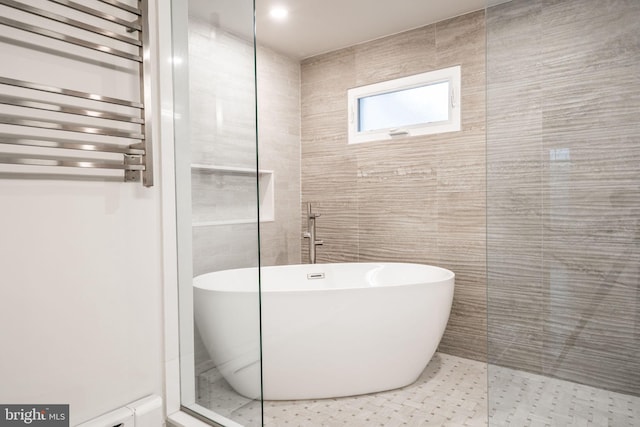 bathroom with a bathing tub, radiator, and tile walls