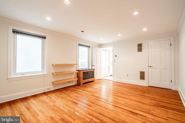 unfurnished living room with radiator heating unit, ornamental molding, and light hardwood / wood-style floors