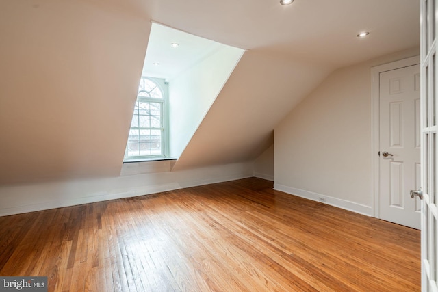 additional living space featuring light hardwood / wood-style floors and vaulted ceiling