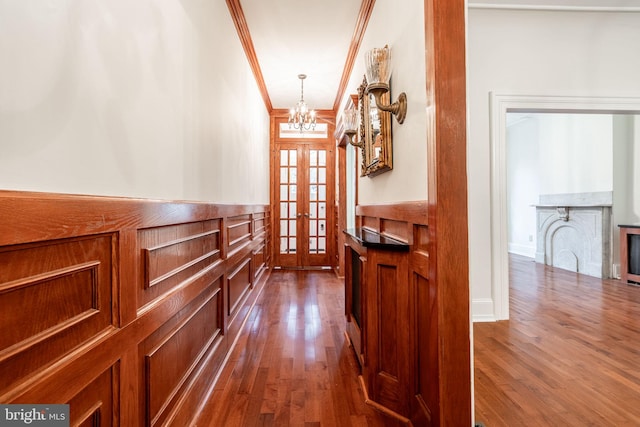 hall with crown molding, dark hardwood / wood-style flooring, a chandelier, and french doors