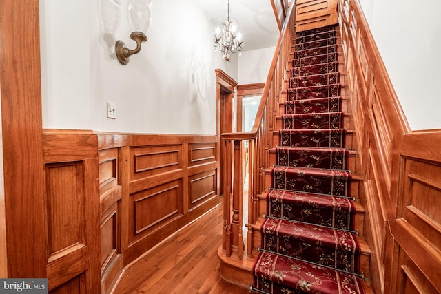 stairway featuring a notable chandelier and wood-type flooring