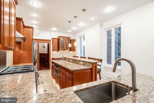 kitchen featuring decorative light fixtures, tasteful backsplash, sink, light stone counters, and stainless steel appliances