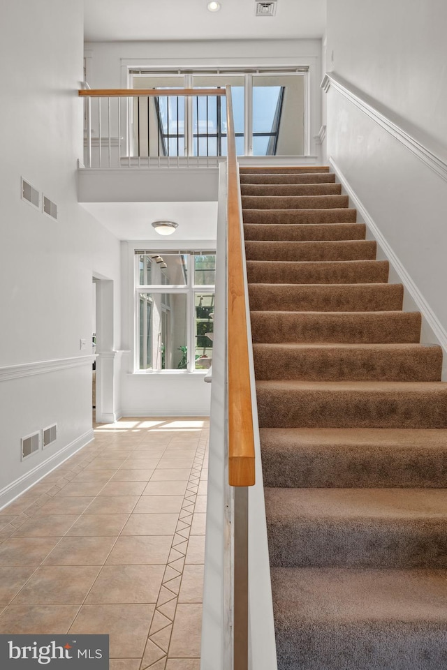 staircase featuring tile patterned floors and a high ceiling