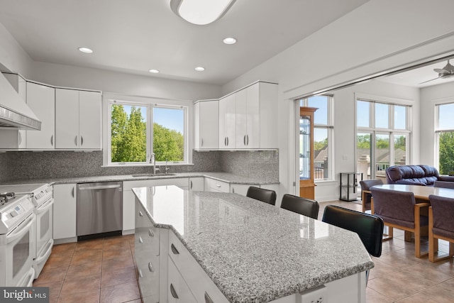 kitchen with sink, white cabinetry, stainless steel dishwasher, and a kitchen island