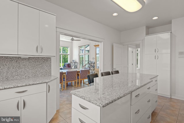 kitchen featuring ceiling fan, white cabinets, and light stone counters