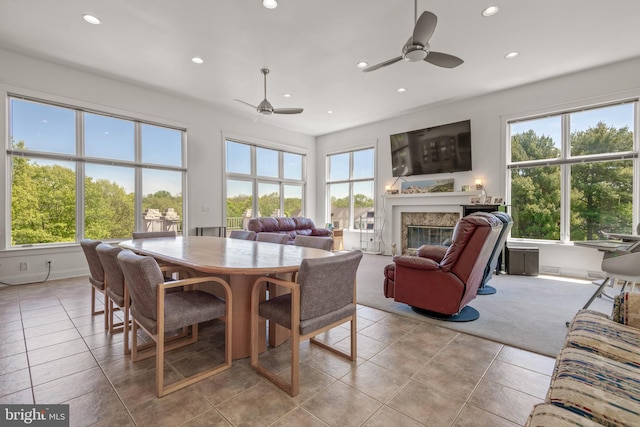 dining space featuring ceiling fan, light tile patterned floors, and a premium fireplace