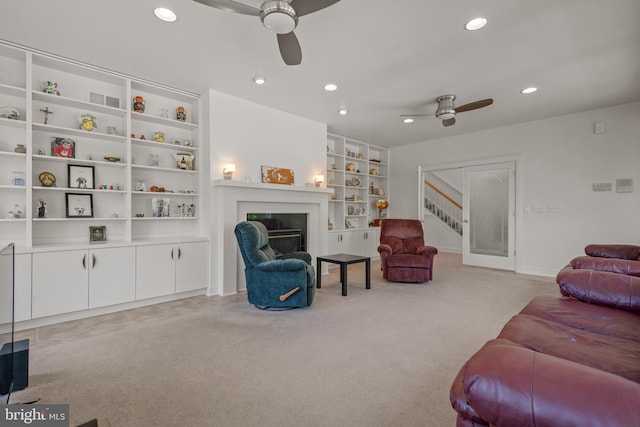 living room with ceiling fan, built in shelves, and light carpet