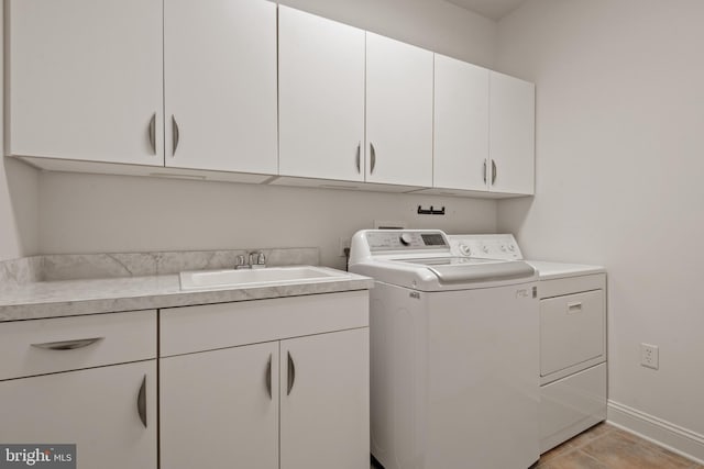 laundry room with light tile patterned floors, washing machine and dryer, sink, and cabinets