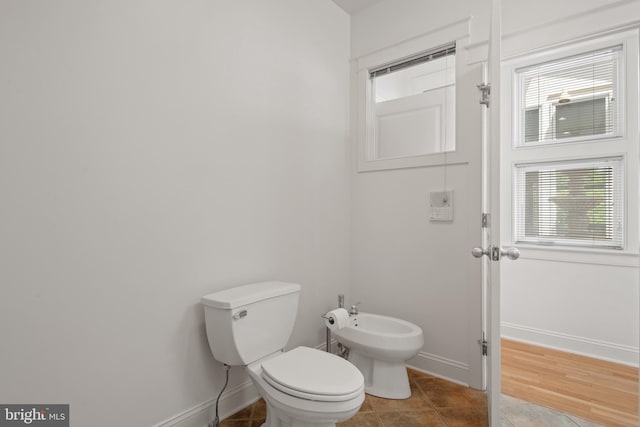 bathroom featuring toilet, tile patterned flooring, and a bidet