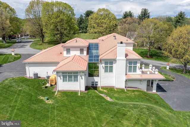 rear view of house featuring cooling unit, a yard, and solar panels