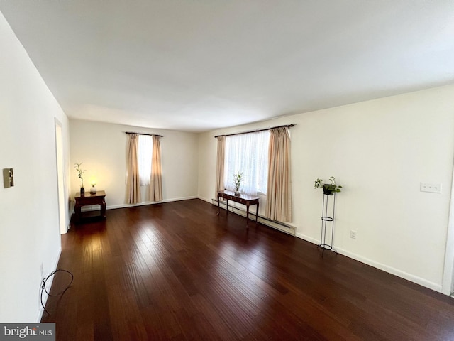 spare room featuring dark wood-type flooring and a baseboard radiator