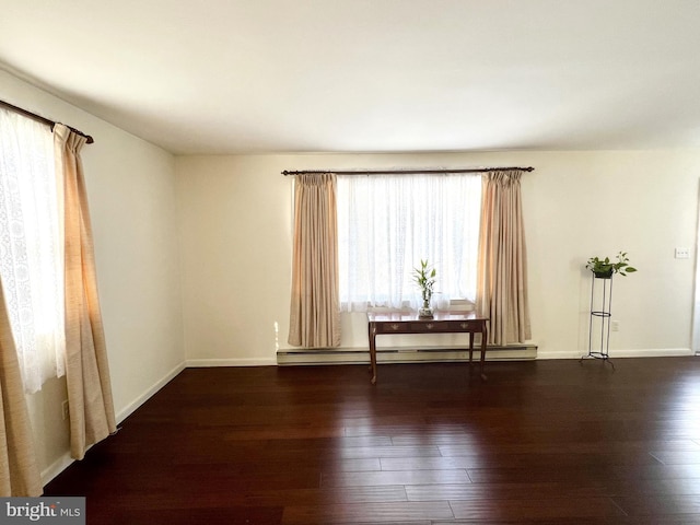 unfurnished room with dark hardwood / wood-style flooring and a baseboard radiator