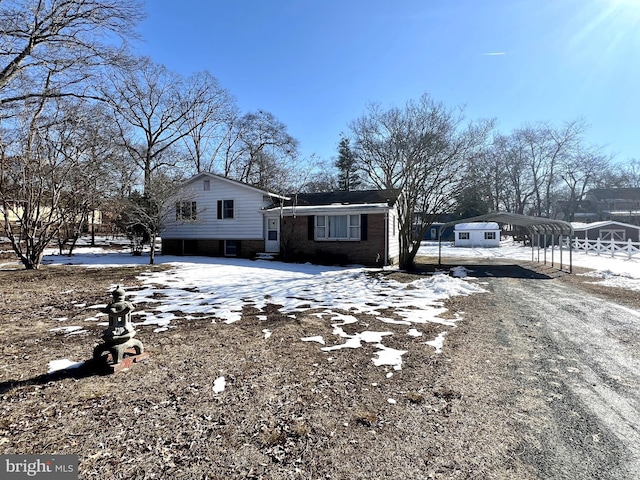 view of front facade featuring a carport, brick siding, and dirt driveway