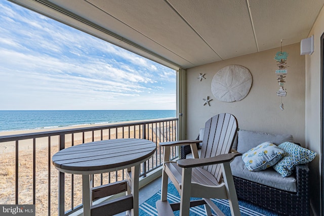 balcony with a water view and a view of the beach